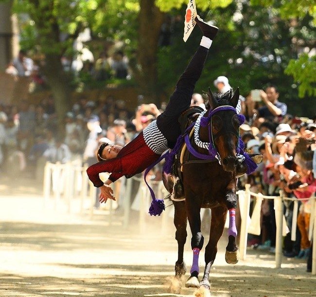 kỵ sĩ thực hiện động tác mạo hiểm trên lưng ngựa phi nước đại trong nghi lễ kakeuma
